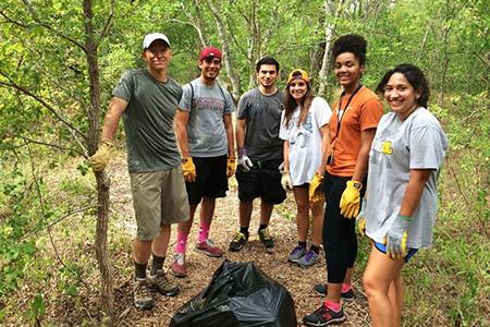 students in the woods with a trash bag and shovel