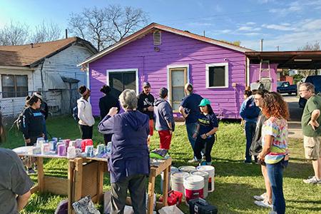 students working outdoors in front of a purple house